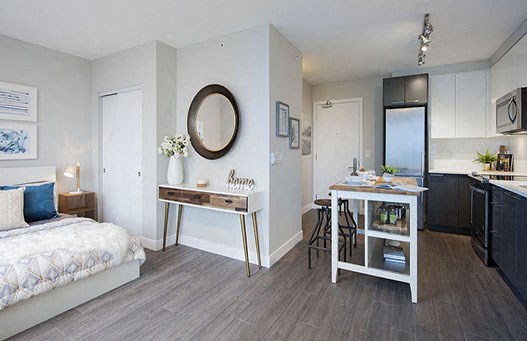 Bachelor apartment with view of the bed and a circular mirror