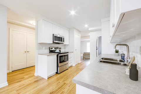 a renovated kitchen with white cabinets and stainless steel appliances