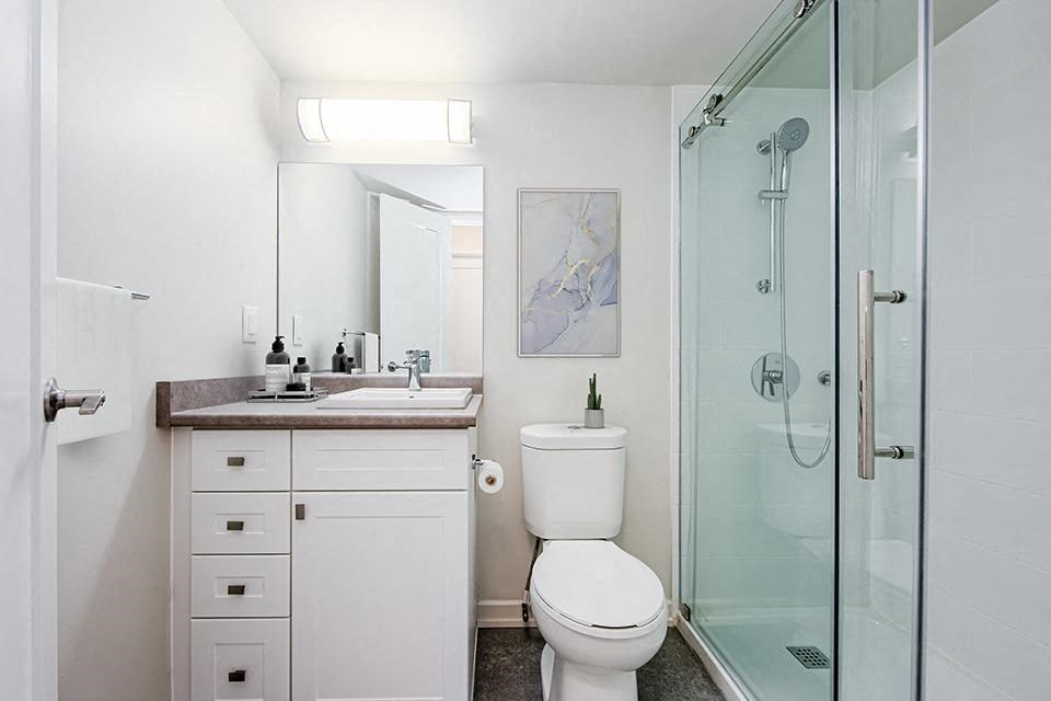 Bathroom with walk-in shower to the right side and vanity with four drawers and cabinet space at Park Place Apartments in Bradford, ON