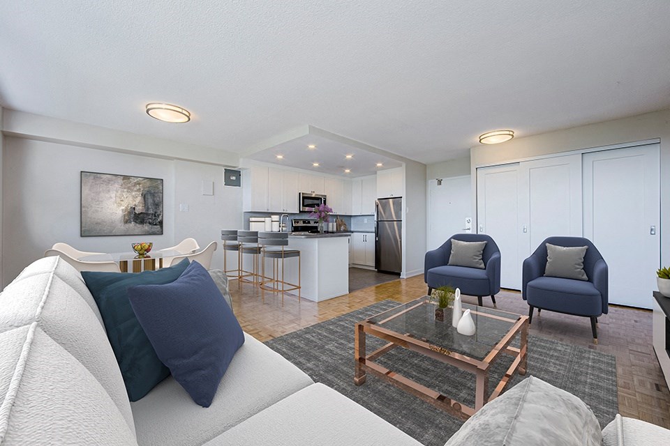Park Place Apartments in Bradford, ON open concept living area with couch and two arm chairs, showing kitchen and dining area in background