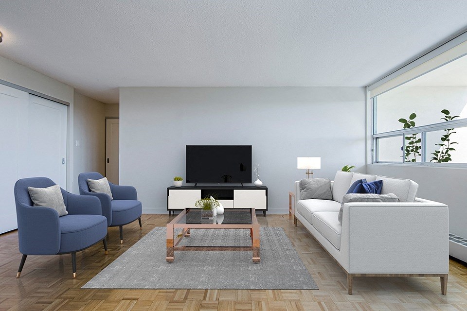 Living room at Park Place Apartments in Bradford, looking towards flat screen TV on entertainment console with two arm chairs on the left, coffee table in the middle and couch on the right