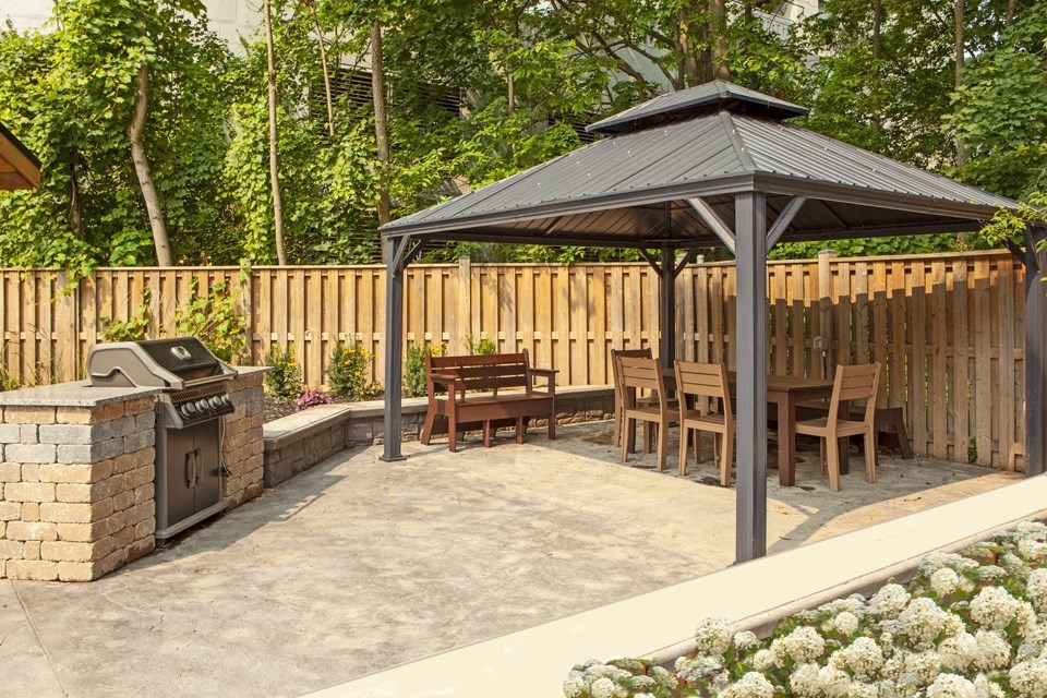 a patio with a gazebo and a grill