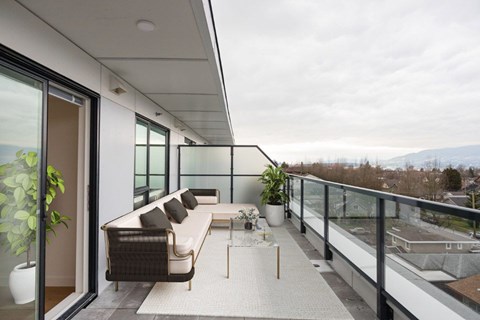 A balcony with a couch and a table with a potted plant on it at 388 Kaslo East Village.