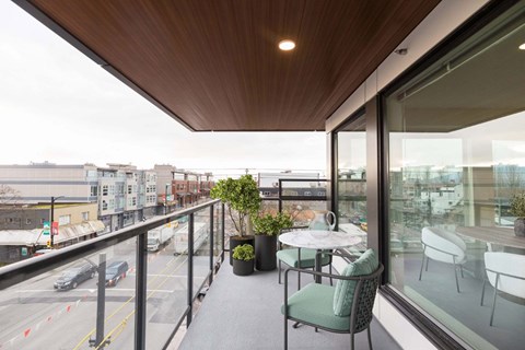 A balcony with a table and chairs overlooking a busy street at 388 Kaslo East Village.