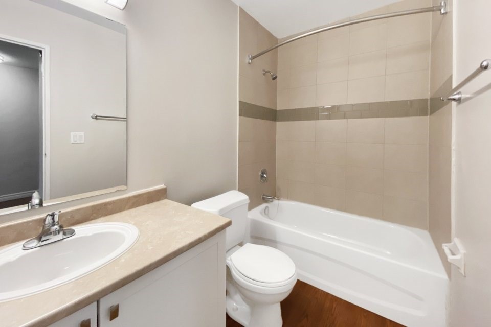 A white toilet sits next to a white bathtub in a bathroom.