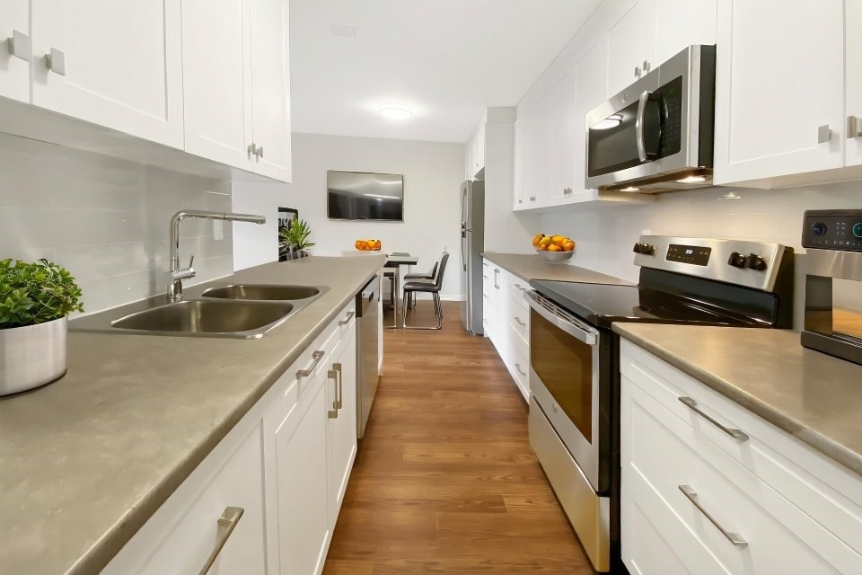 A modern kitchen with white cabinets and stainless steel appliances.
