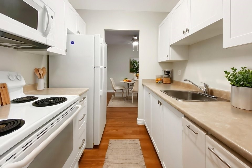 A kitchen with white appliances and cabinets.