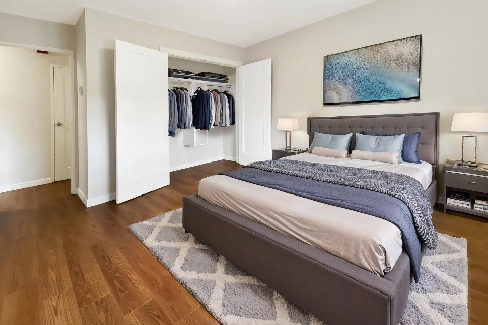 A bedroom with a large bed and a clothing closet.