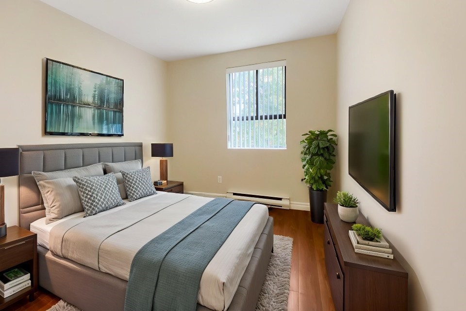 A bedroom with a large bed and a flat screen TV mounted on the wall.