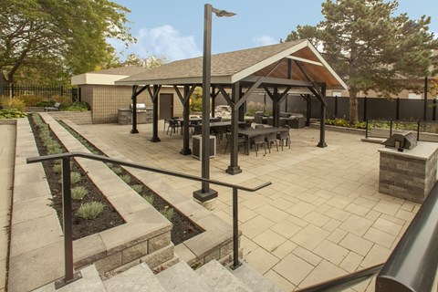 A patio with gazebo a table and chairs and a black fence  at Prince William Apartments in Belleville