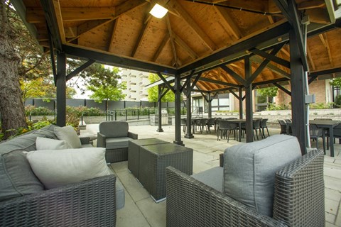 A patio with grey wicker furniture under a gazebo  at Prince William Apartments in Belleville