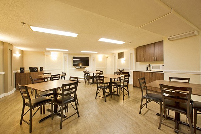 Regency Place social room with tables and chairs and tv in Whitby, ON
