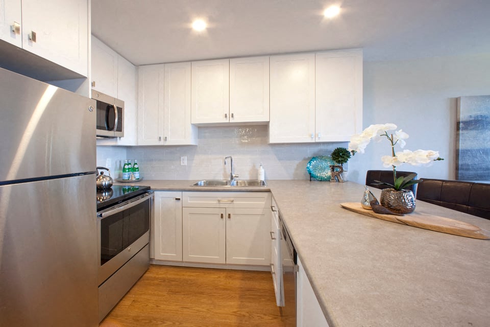 Regency Towers modern kitchen with white cabinetry and stainless steel appliances in St. Catherines, ON