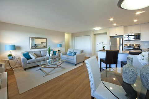 A modern living room with a glass table and white chairs.