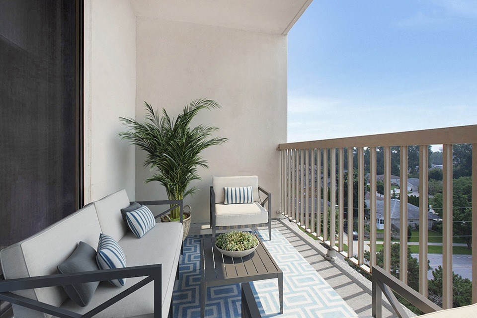 Balcony with outdoor couch, chair, table and large plant at Riverbend Tower Apartments in Chatham, ON