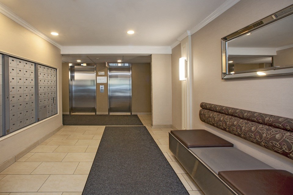 Lobby, looking towards elevators, with bench seating on right side and mailboxes on left side, at Riverbend Tower Apartments in Chatham, ON