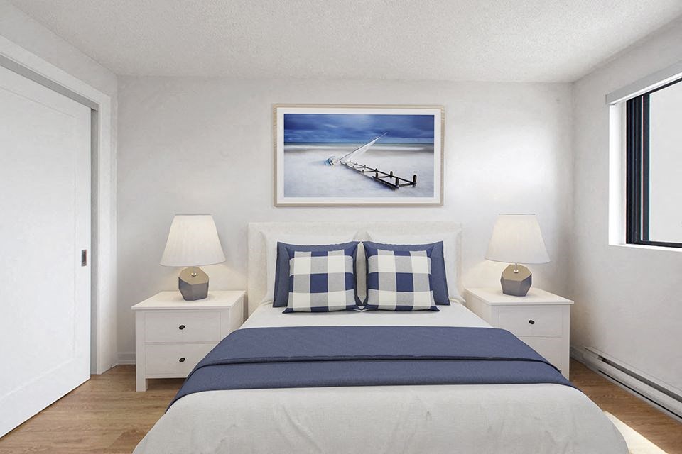 Primary bedroom with queen size bed at Riverbend Tower Apartments in Chatham, ON