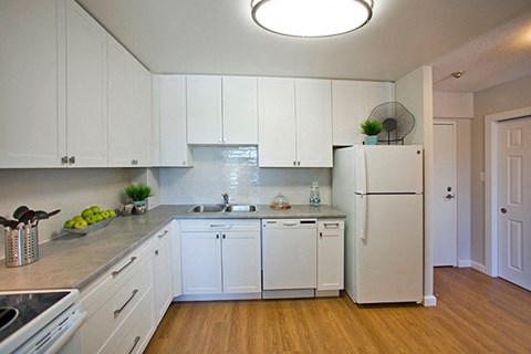 A kitchen with white cabinets and a white fridge.
