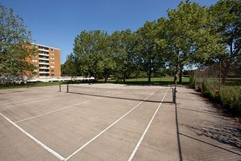 a tennis court with trees and a building in the background