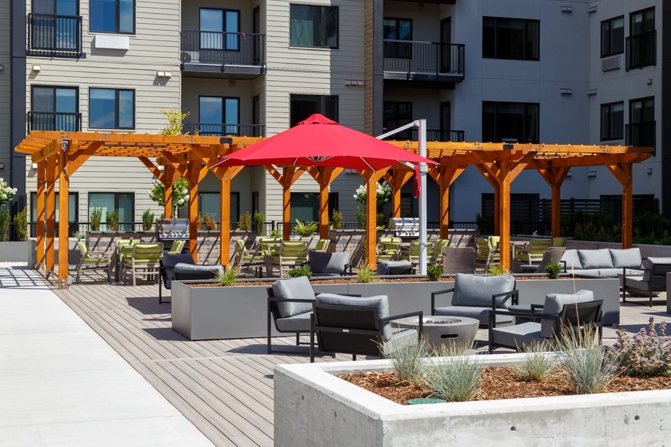 A patio with a red umbrella and chairs at The Ambrosi in Kelowna, BC.