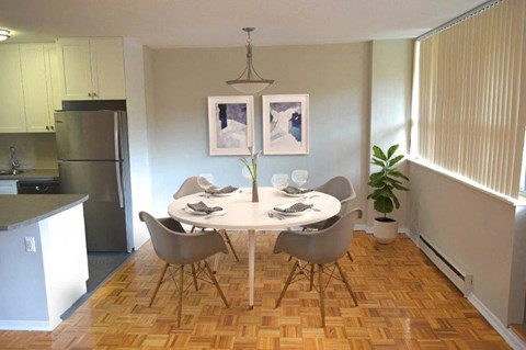 A dining room with a table set for two and a potted plant.