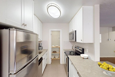 A kitchen with a refrigerator on the left and a microwave above the stove.
