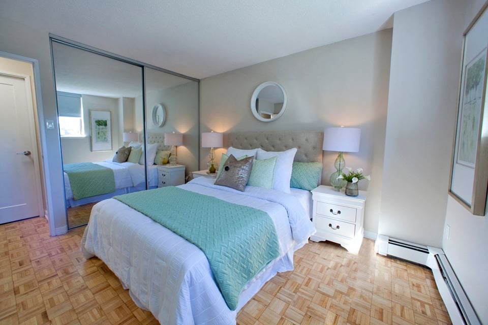 Sunnidale Place Modern bedroom with white covers and light blue blankets and mirrored closet doors in Barrie, ON