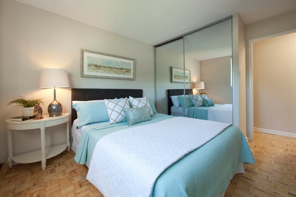 Sunnidale Place Modern bedroom with airy, light blues and whites. A mirror door closet is to the right of the bed in Barrie, ON