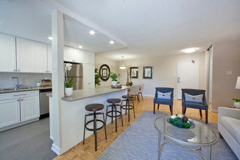 A modern kitchen with white cabinets and a bar area with stools.