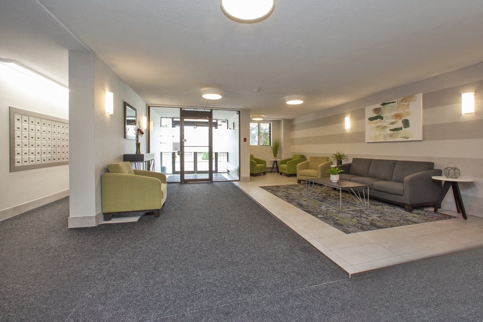 Main lobby at Sunnidale Place in Barrie, ON looking towards main door and showing couch and club chair seating and mail room