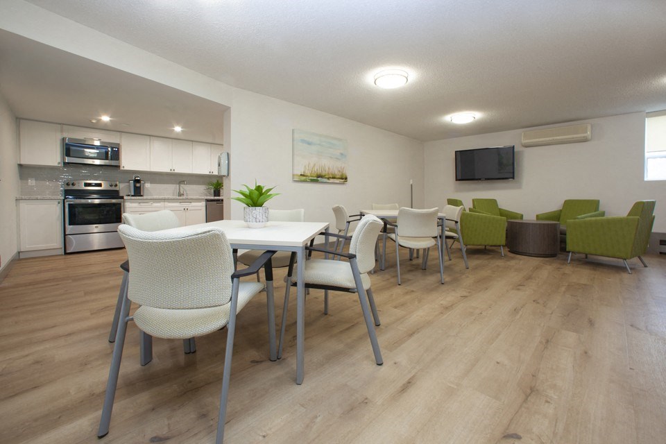 Social room at Sunnidale Place in Barrie, ON featuring kitchen, tables and chairs, comfy lounge seating and flat screen TV