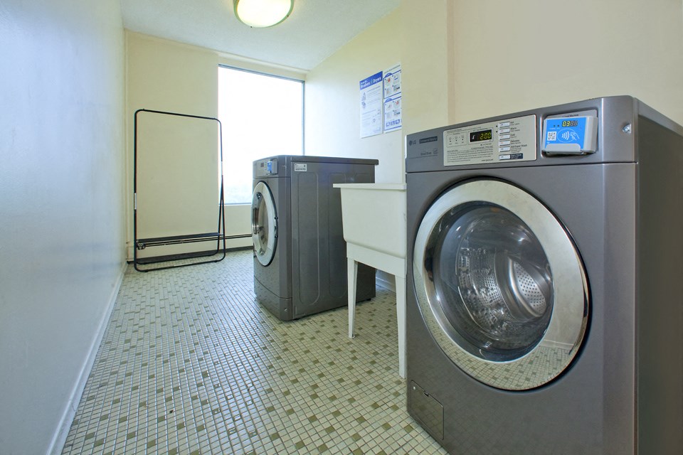 Sunset Towers laundry room with front loader washer and dryer with smart card system and laundry sink in St. Thomas, ON