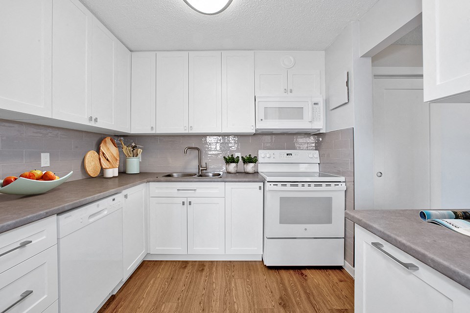 Sunset Towers kitchen with white shaker-style cabinetry, dishwasher, stove and over-the-range microwave in St. Thomas, ON
