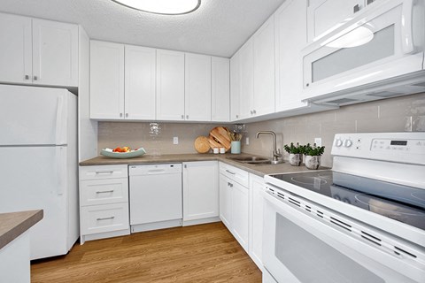 Sunset Towers kitchen with white cabinetry, fridge, dishwasher, stove and over-the-range microwave in St. Thomas, ON