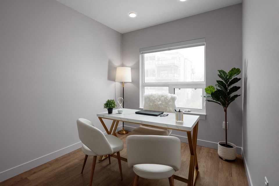 A white desk with a lamp and two chairs in a room at The Ambrosi in Kelowna, BC.