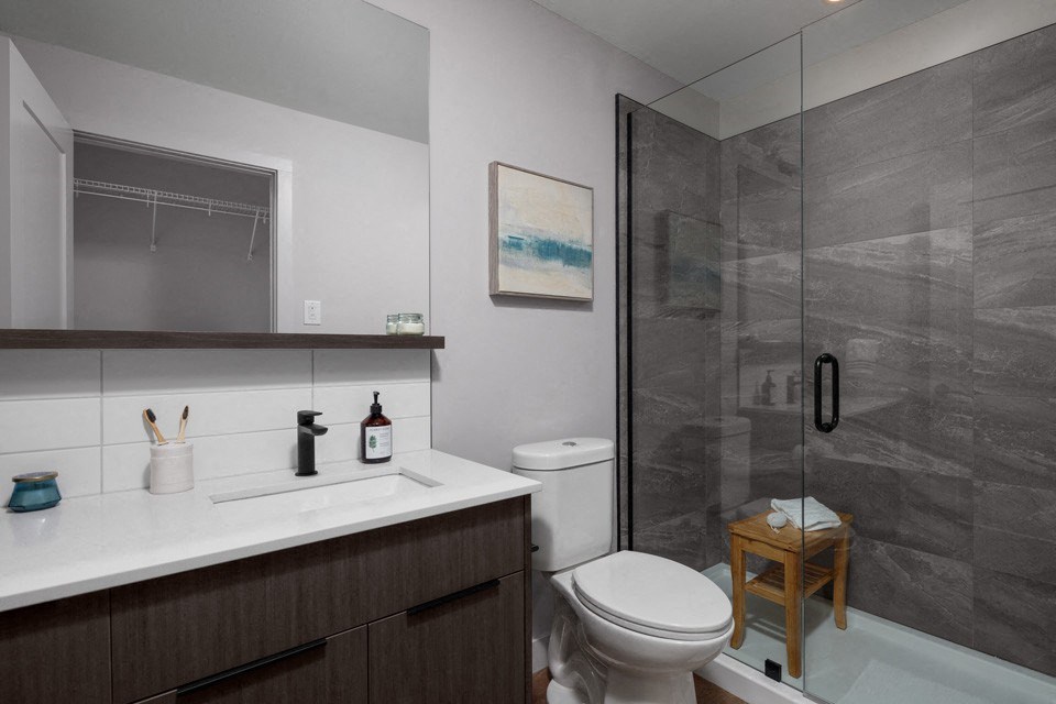 A bathroom with a toilet, sink, and a shower at The Ambrosi in Kelowna, BC.