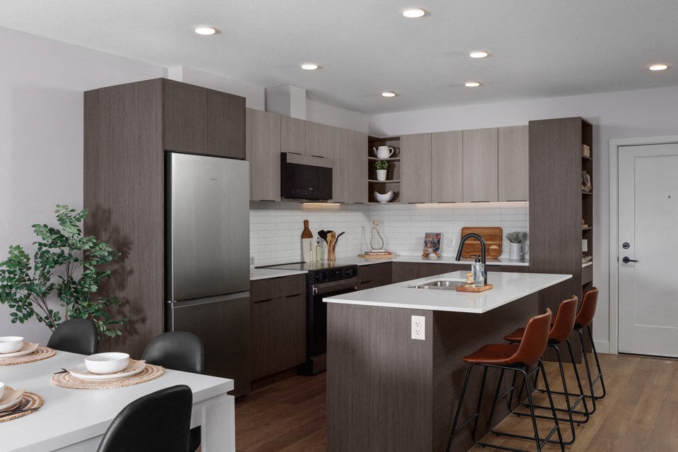 A modern kitchen with a dining table set for two at The Ambrosi in Kelowna, BC.