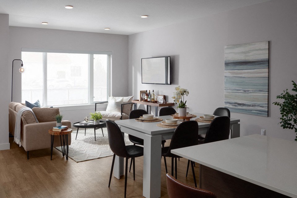 A modern dining room with a white table and black chairs at The Ambrosi in Kelowna, BC.