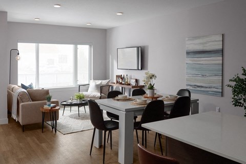 A modern dining room with a white table and black chairs at The Ambrosi in Kelowna, BC.