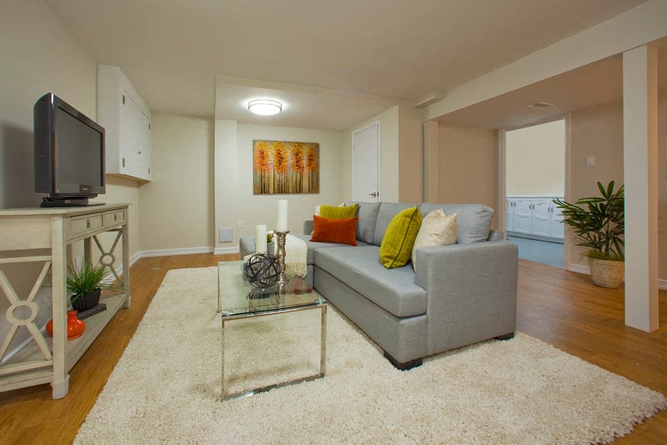 Tamarack Woods Cozy open concept basement with a soft white rug, a tv, and a couch in Barrie, ON
