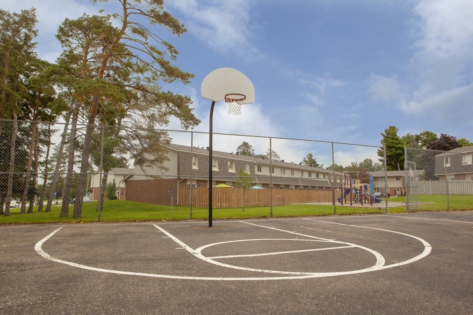 Outdoor basketball court, showing playground in the background at Tamarack Woods in Barrie, ON
