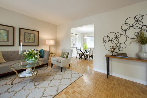 A living room with a glass coffee table and a grey sofa.