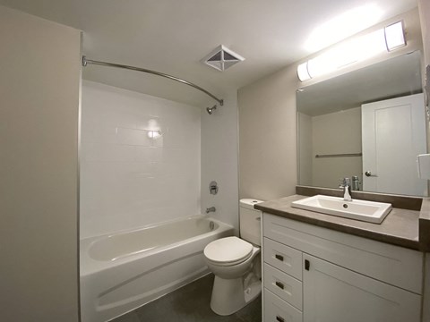 Refinished bathroom at Tarawood Place in Peterborough feature large vanity with drawers and cupboard storage and top-mount sink and tub with shower and curved shower rod