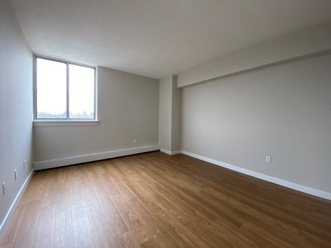 Primary bedroom in a two bedroom suite looking towards sliding glass window at Tarawood Place in Peterborough, ON