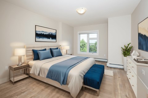 a bedroom with white walls and a bed with blue pillows