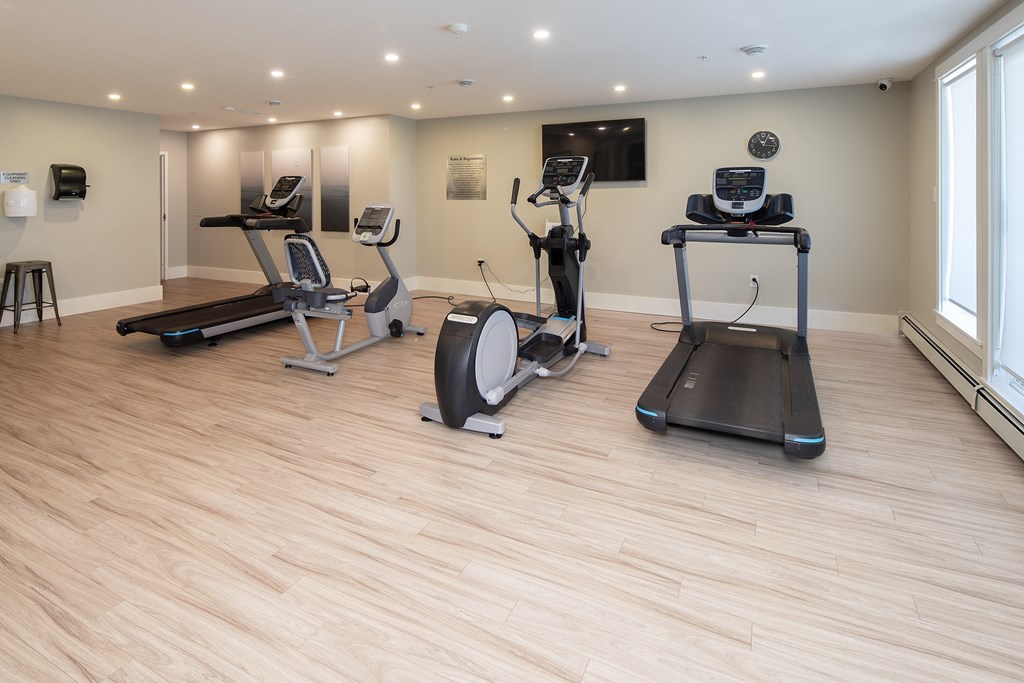 a gym with treadmills and other exercise equipment on a wood floor