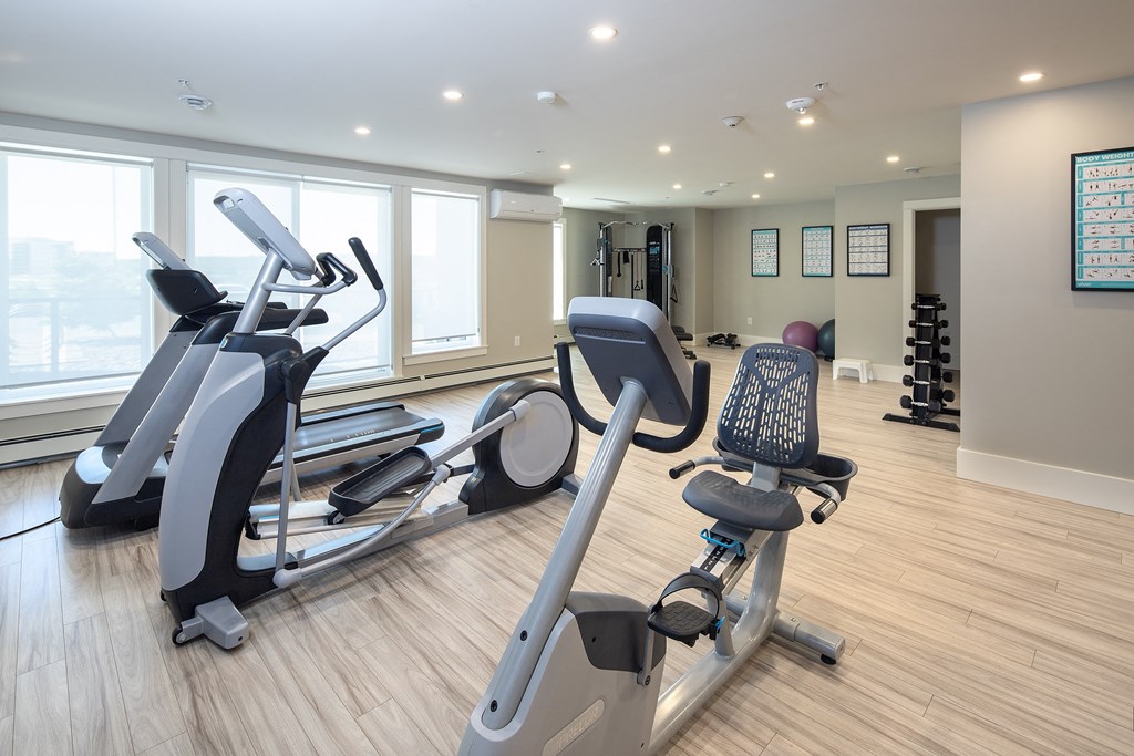 a gym with cardio equipment and windows in a building