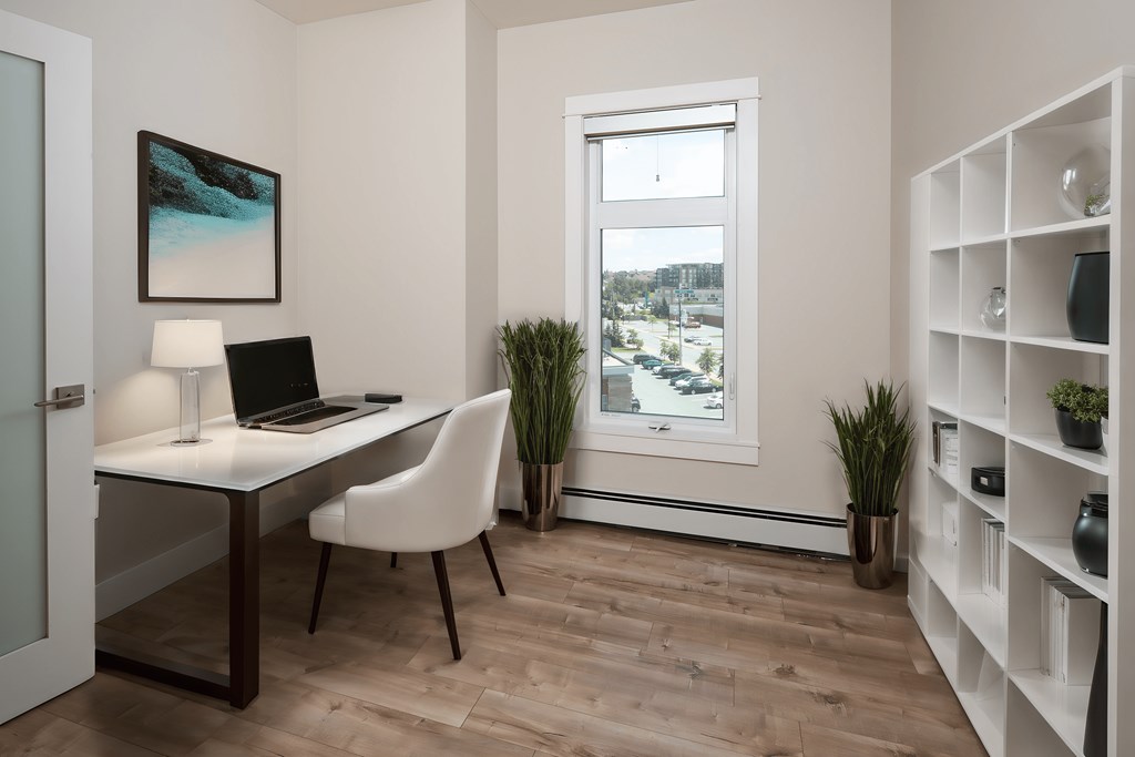 a home office with a laptop on a desk and a window
