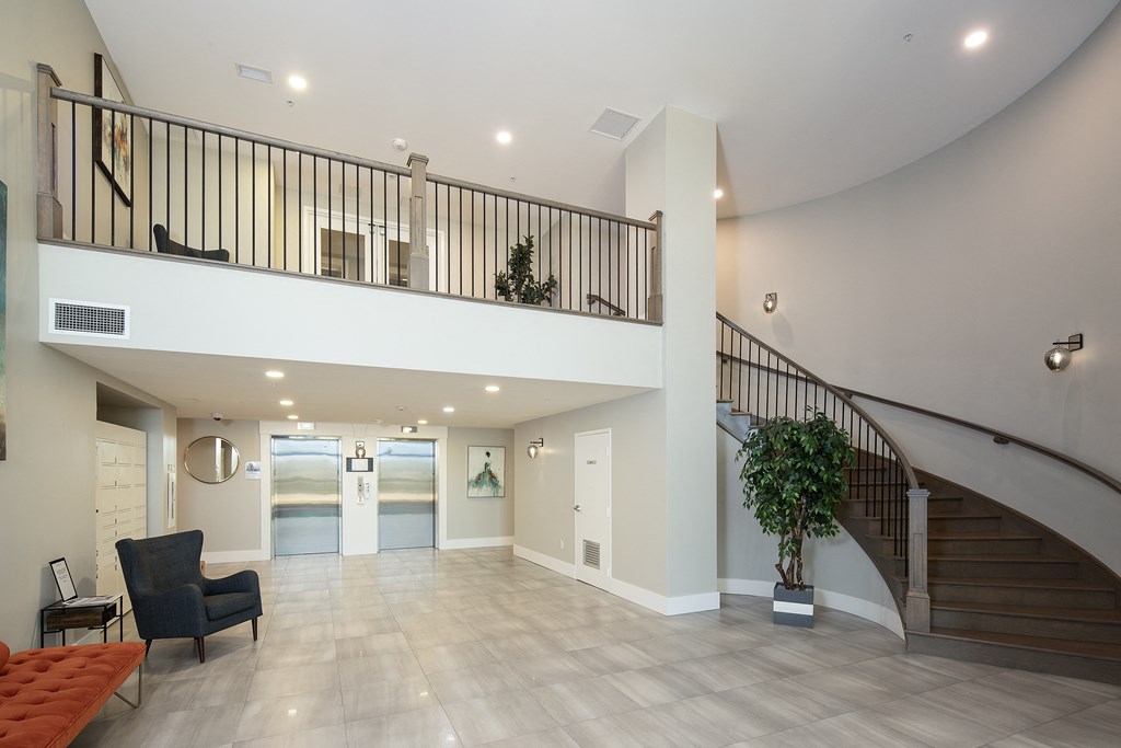 a lobby with a staircase and a lobby area with a couch and a chair