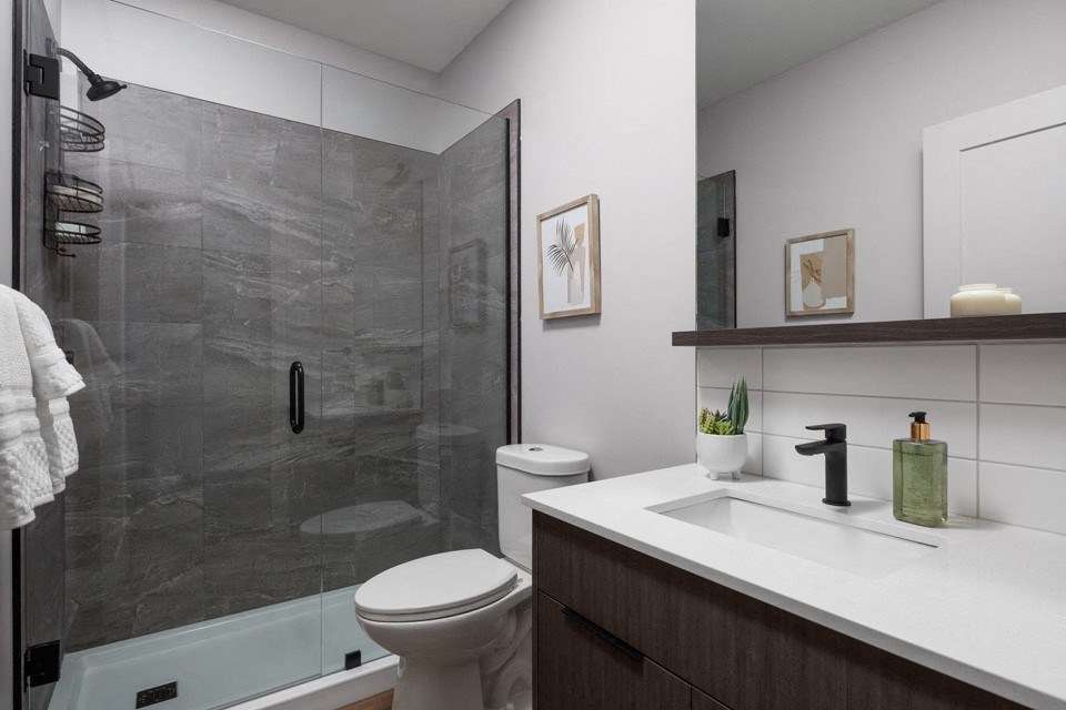 A modern bathroom with a walk-in shower and a toilet at The Ambrosi in Kelowna, BC.